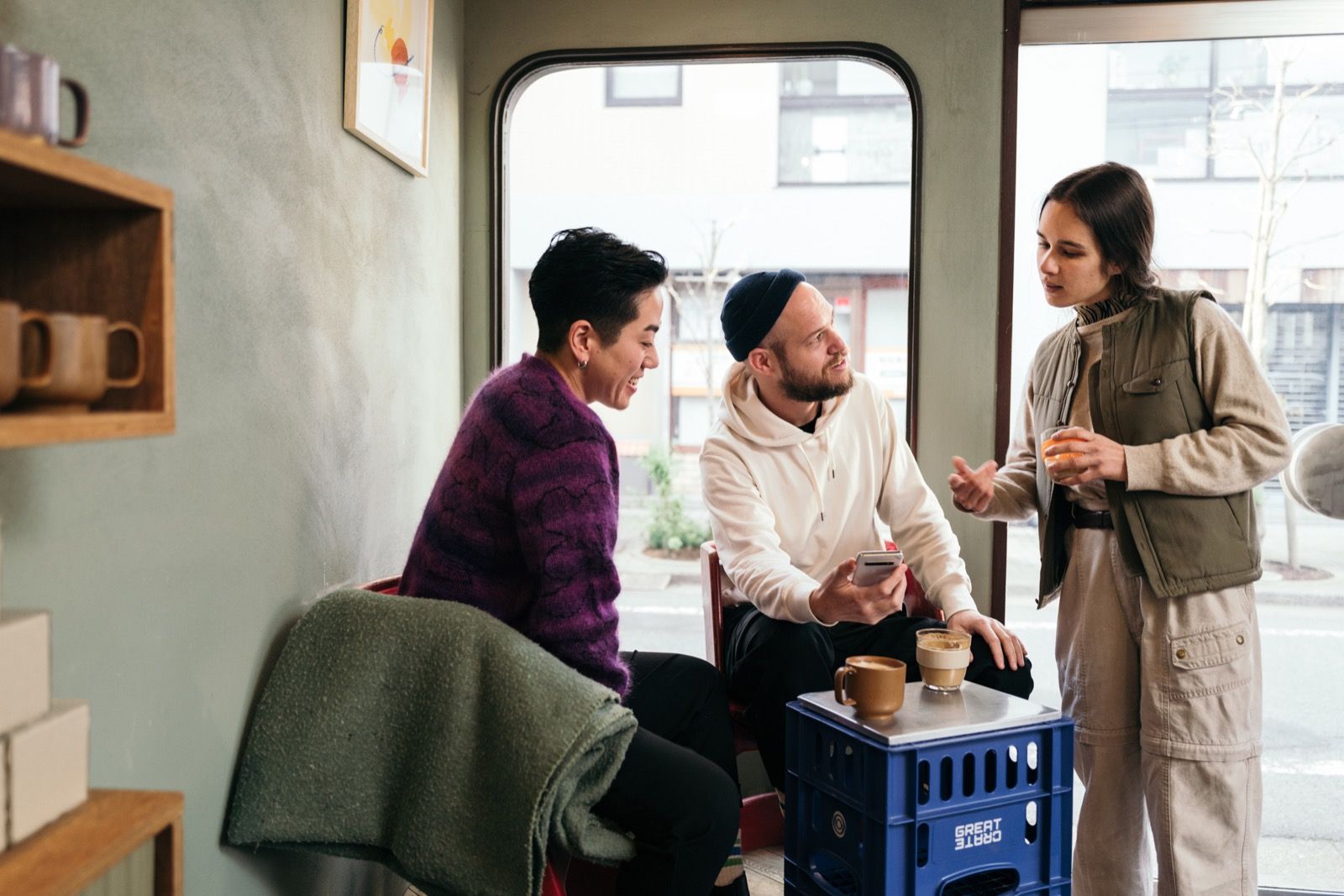 Three people talking over coffee in a neighbourhood cafe